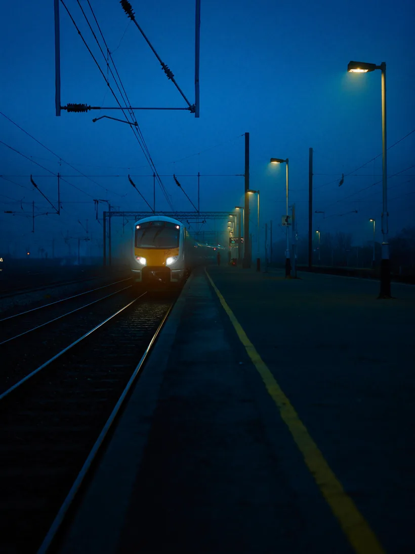 Commuter train at a station platform before dawn